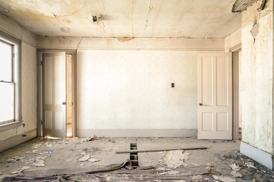 Antes: habitación con paredes desconchadas y el suelo levantado