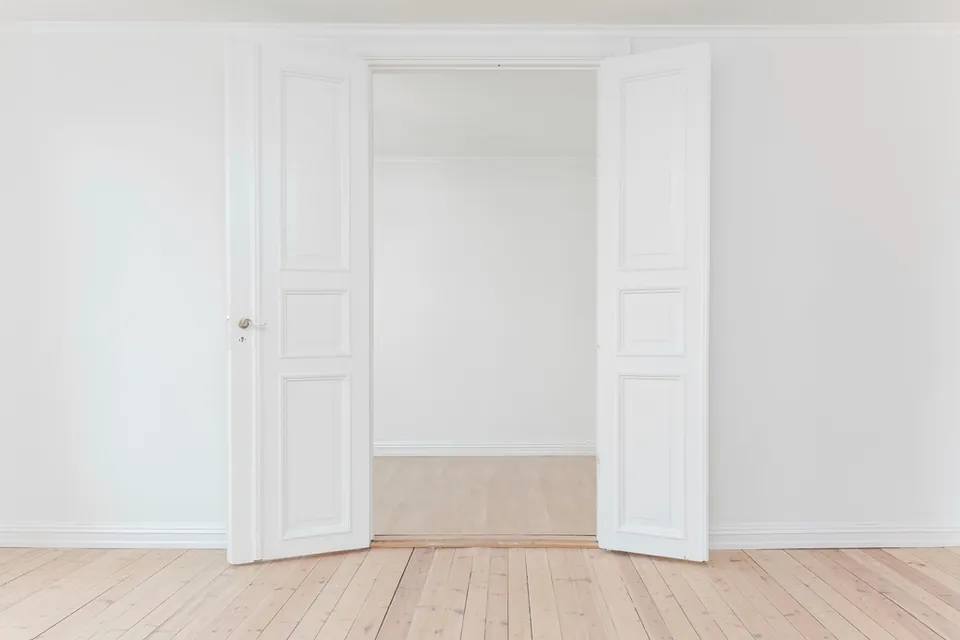 Después: estancia con paredes lisas, puertas lacadas en blanco y suelo de madera natural